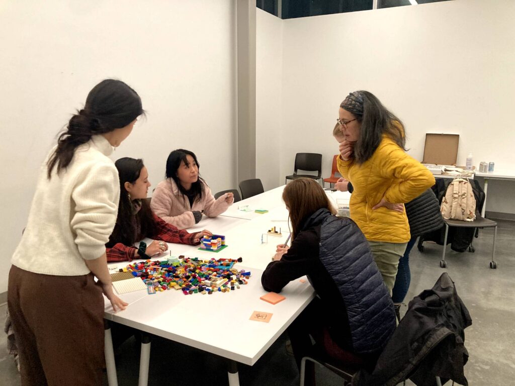 Participants around the table, planning their desktop walkthrough build with LEGO